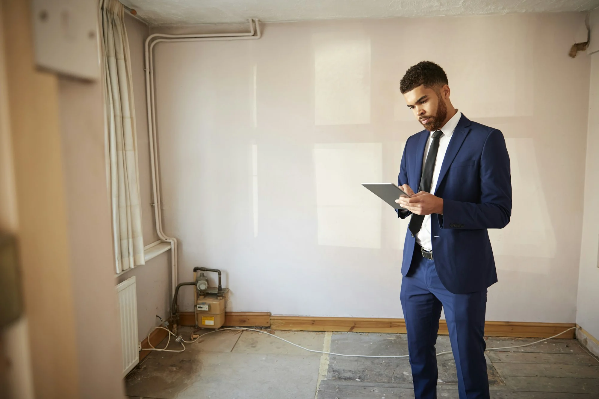 Male Realtor With Digital Tablet Carrying Out Valuation On Property For Renovation